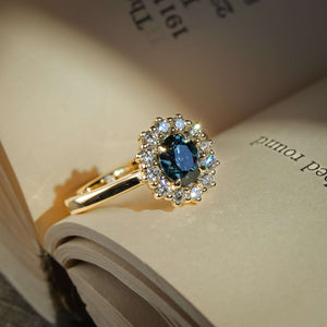 Oval teal sapphire engagement ring with diamond cluster halo setting
