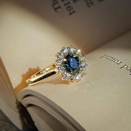 Oval teal sapphire engagement ring with diamond cluster halo setting