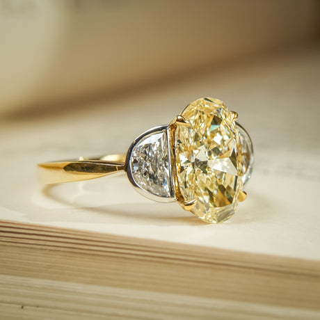 Oval yellow diamond engagement ring with half moon diamond accents