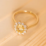 Yellow sapphire and diamond cluster ring showcasing a radiant oval-cut yellow sapphire framed by brilliant white diamonds.