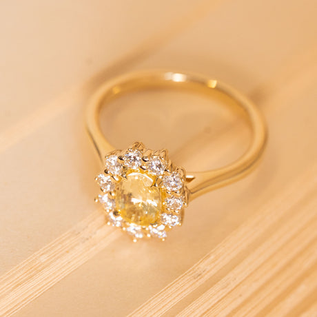 Yellow sapphire and diamond cluster ring showcasing a radiant oval-cut yellow sapphire framed by brilliant white diamonds.