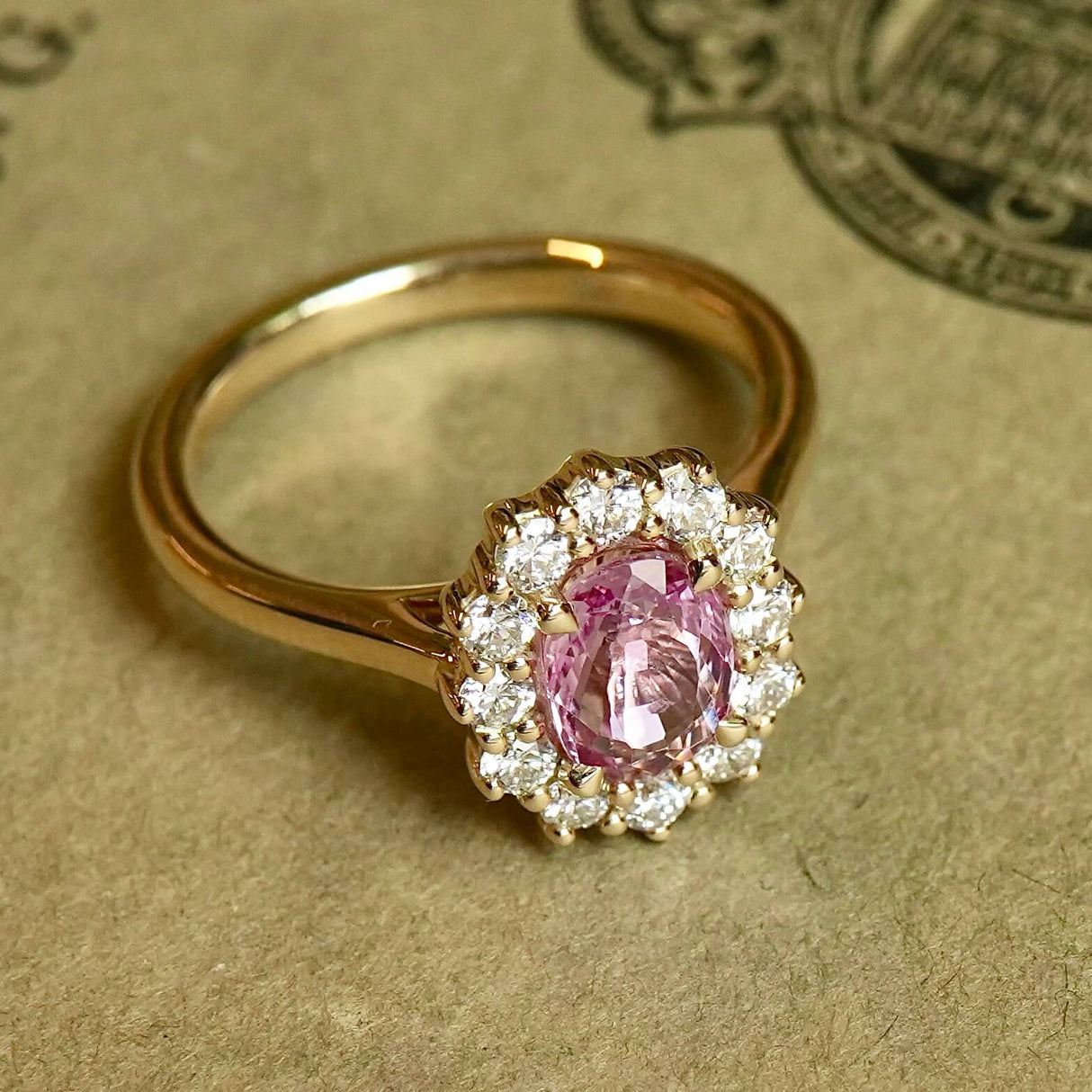 Oval padparadscha pink sapphire engagement ring with diamond cluster setting