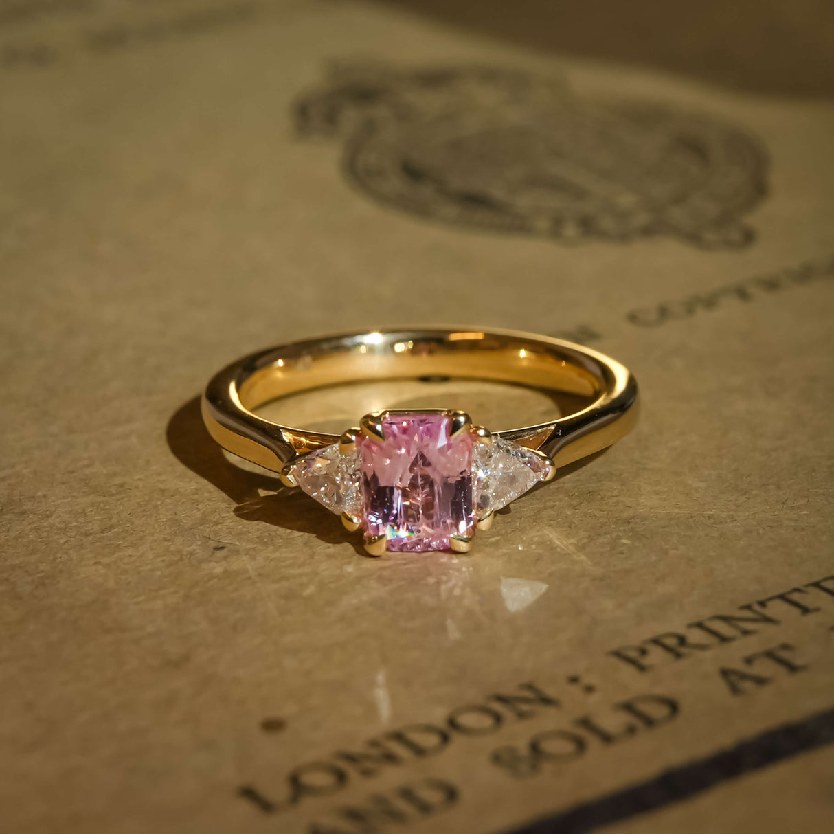 Padparadscha sapphire center stone with trillion diamonds three stone engagement ring