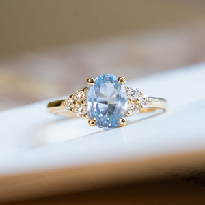 Pale blue sapphire and diamond cluster tre-foil engagement ring with oval sapphire and diamond-set shoulders.