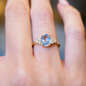 Pale blue sapphire and diamond cluster tre-foil engagement ring with oval sapphire and diamond-set shoulders.