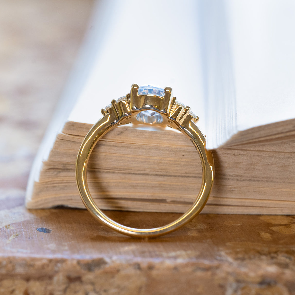 Pale blue sapphire and diamond cluster tre-foil engagement ring with open gallery beneath oval sapphire setting.