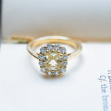 Pale yellow sapphire and diamond cluster engagement ring with yellow gemstone.