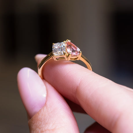 Peach coloured sapphire and diamond Toi et Moi engagement ring with gold band and mixed gemstone setting.