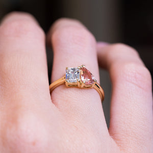 Peach coloured sapphire and diamond Toi et Moi engagement ring with asymmetrical pear sapphire and emerald cut diamond.