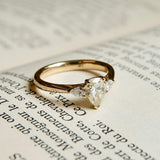 Pear cut diamond three stone engagement ring with diamond side stones in yellow gold