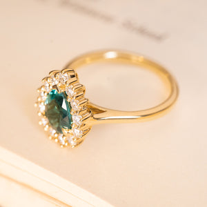 Pear-cut teal tourmaline and diamond cluster engagement ring in polished yellow gold