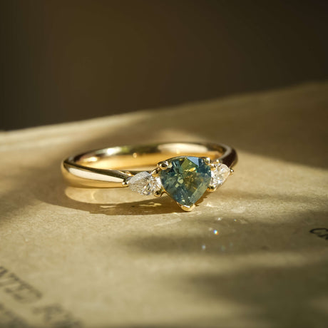 Pear green sapphire with diamond three stone engagement ring in yellow gold