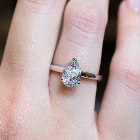 Vintage salt and pepper diamond solitaire ring with pear-shaped diamond worn on hand.