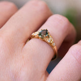 Pine green sapphire and diamond engagement ring with gold setting and diamond side stones.