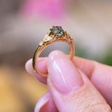 Pine green sapphire and diamond engagement ring showing raised gold setting and diamond detailing.