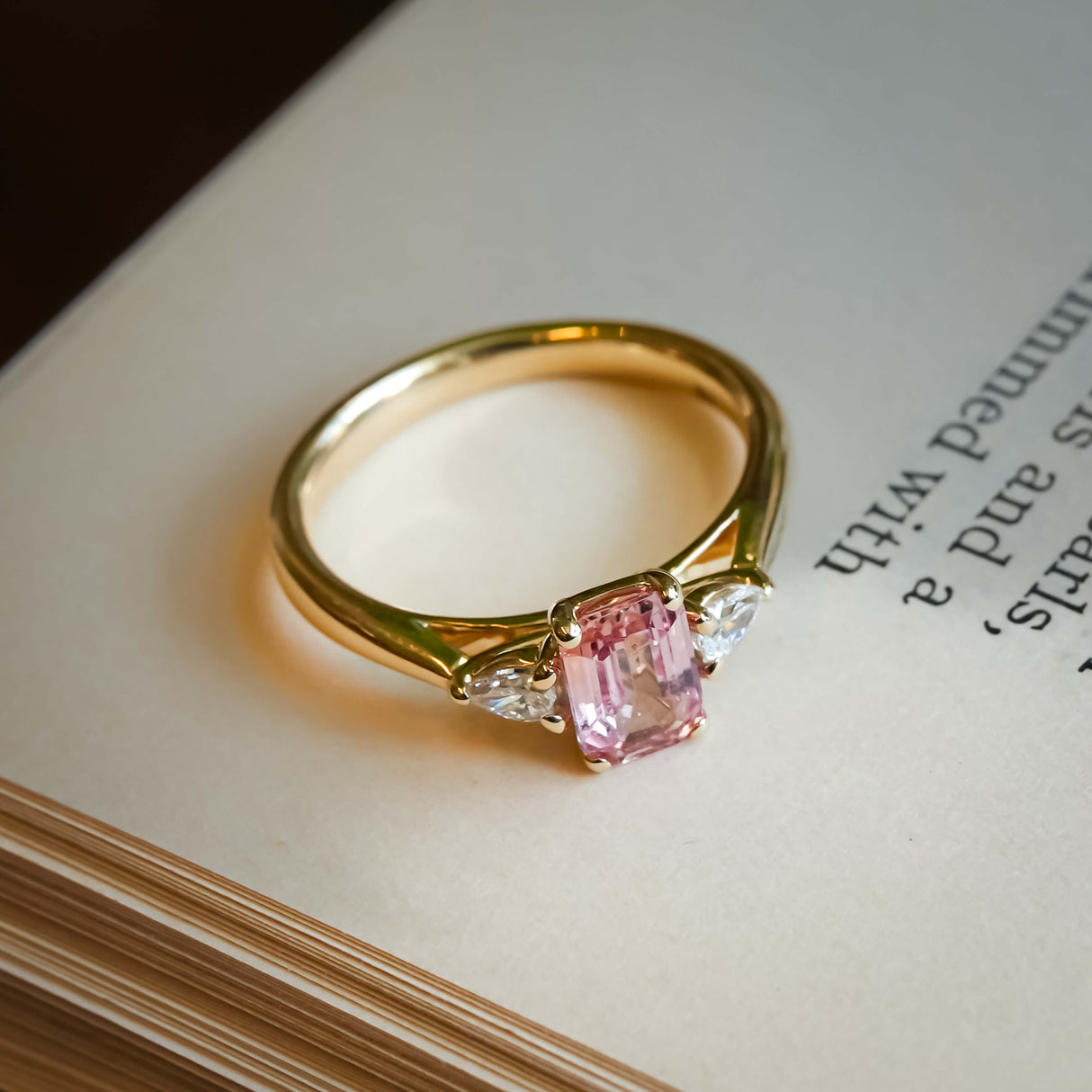Pink sapphire and diamond three stone engagement ring with classic yellow gold setting