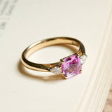 Emerald cut pink sapphire engagement ring with diamond side stones in yellow gold