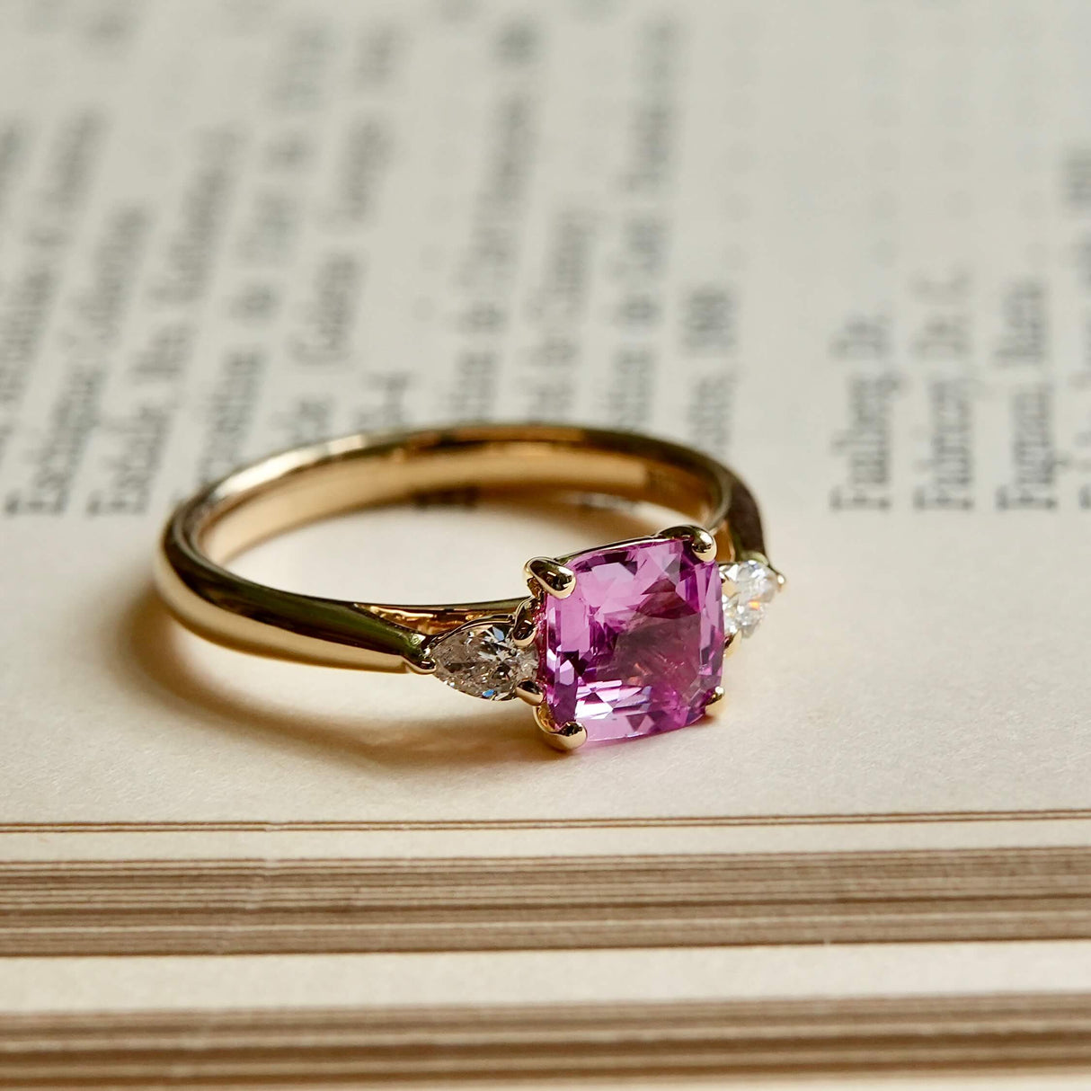 Pink sapphire and diamond three stone engagement ring in yellow gold