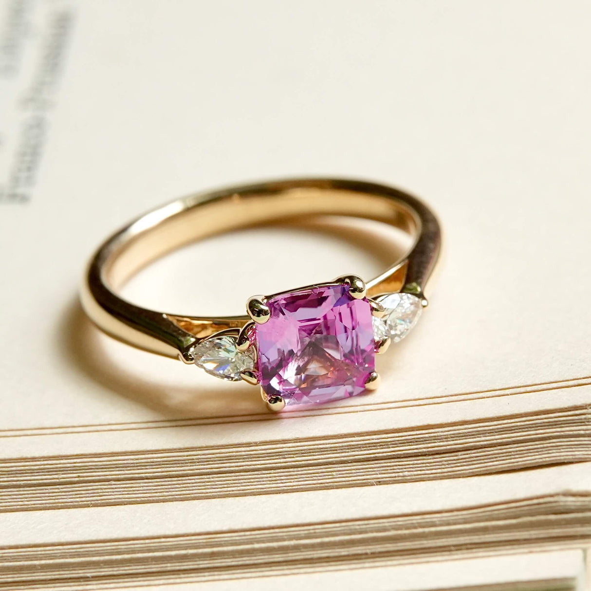 Pink sapphire center stone with diamond side stones engagement ring in yellow gold