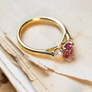 Pink sapphire and diamond three-stone engagement ring with oval pink sapphire centre stone.