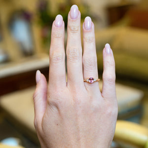Pink sapphire and diamond three-stone engagement ring worn on hand with oval pink sapphire centre stone.