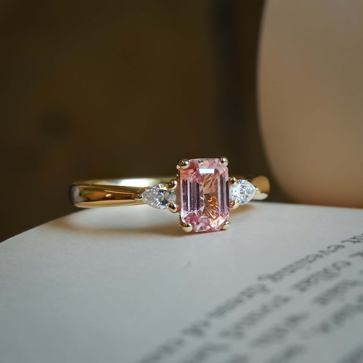 Pink sapphire center stone with trillion diamonds three stone engagement ring