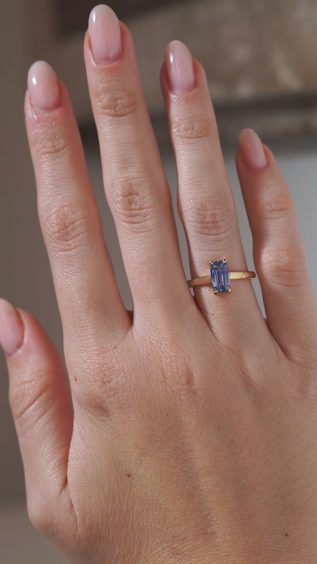 A video of the blue sapphire engagement ring worn on a hand, capturing the gemstone's icy blue reflections and elegant solitaire setting.