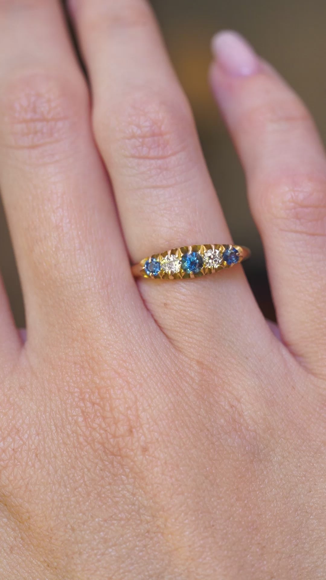 A video of an antique Edwardian blue sapphire and diamond five-stone ring shown on the hand.