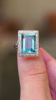 A video of an antique Art Deco aquamarine and diamond cocktail ring in platinum held between the fingers.