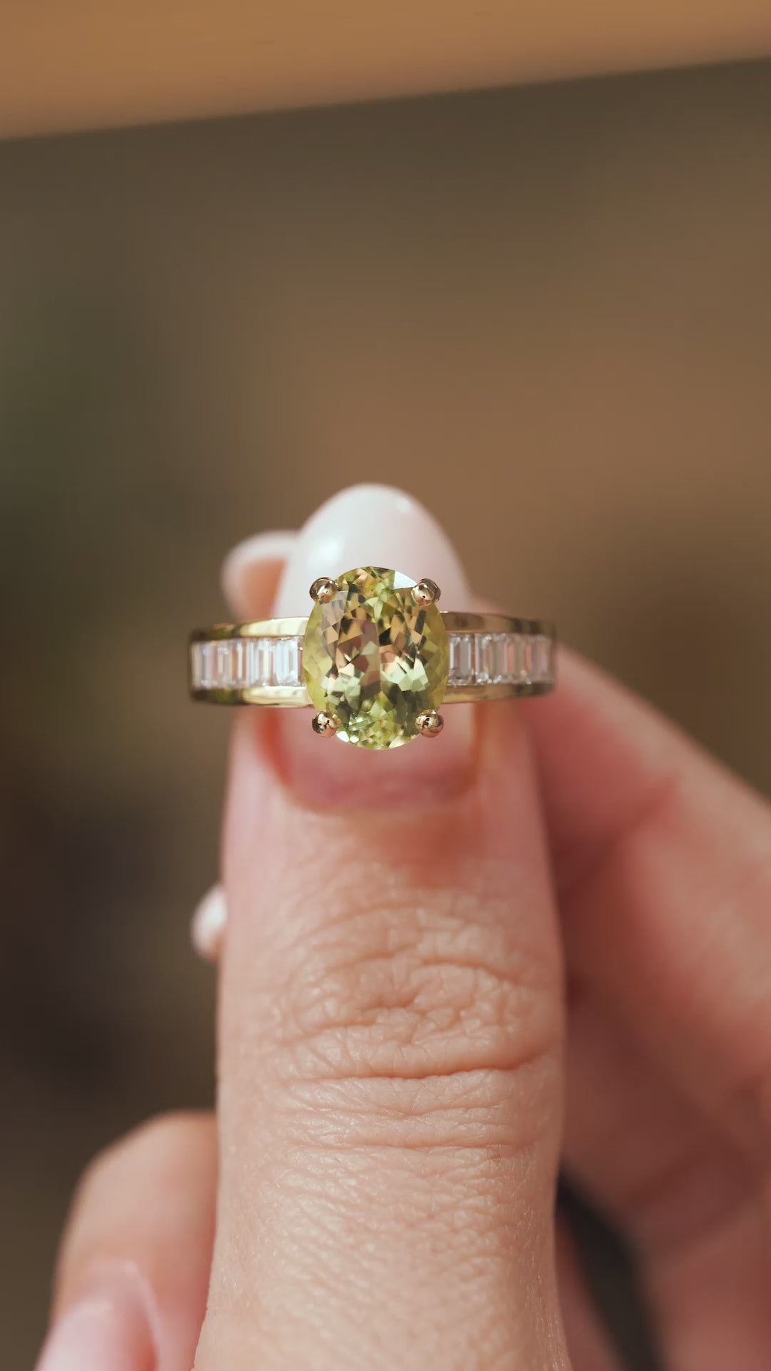 Video close-up of a vintage 1980s green beryl solitaire ring balanced on a fingertip, displaying its baguette diamond shoulders.