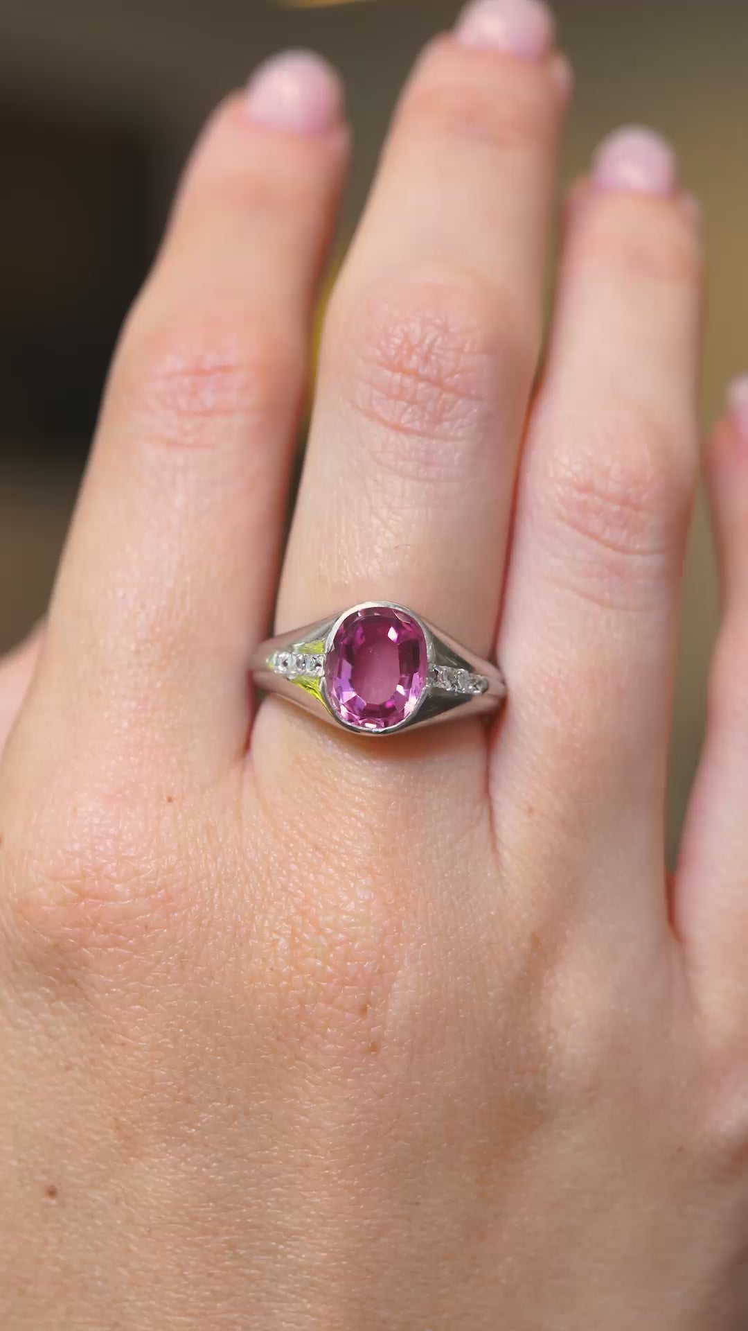 A video of a hand wearing a Vintage, 1940s pink sapphire and diamond gypsy ring from a distance.