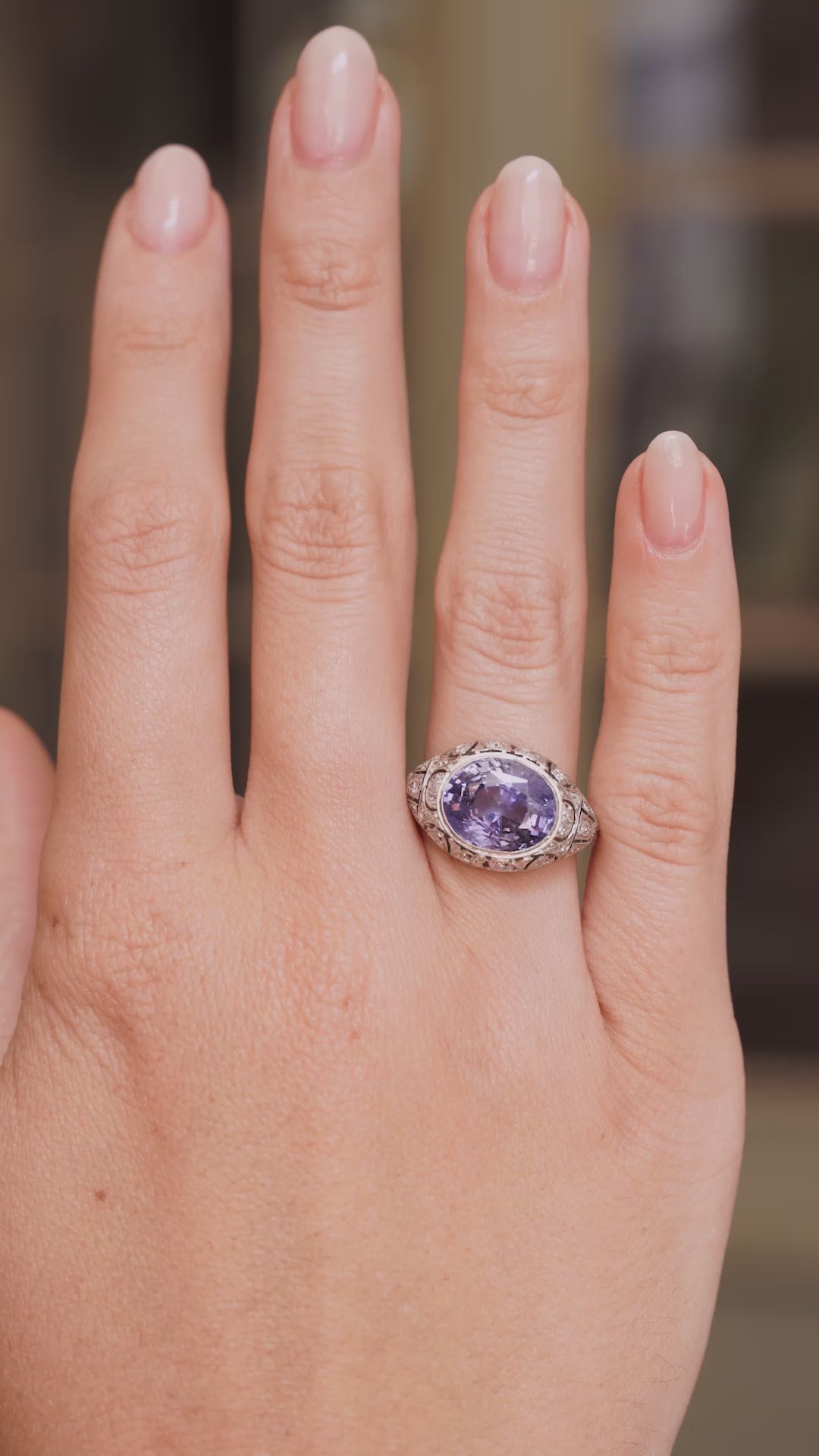 A video of an Antique, Belle Époque Ceylon colour-change sapphire and diamond cluster ring in platinum worn on the hand and outstretched to show scale