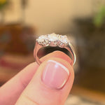 Vintage diamond three stone ring in white gold held in between the fingers and turned to show different angles of the ring,