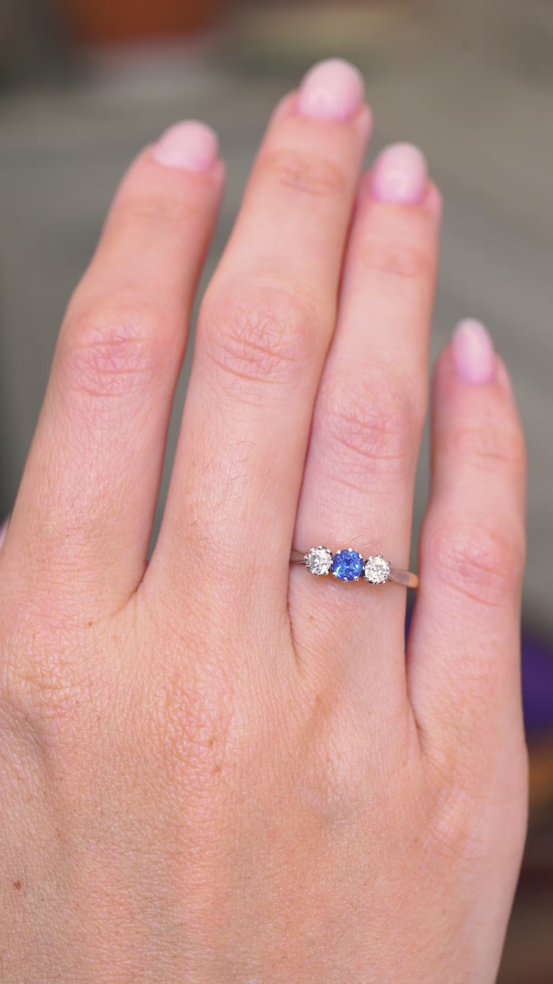 A video of an outstretched hand wearing an antique Edwardian blue sapphire and diamond three-stone engagement ring shown from a distance to showcase the proportions of the ring.