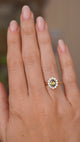 A video of a hand wearing an Antique-inspired, Green oval sapphire and diamond cluster engagement ring.  Worn on a wedding finger and rotated slowly to showcase the wedding fit profile of the ring once worn and the yellow gold setting and band.  