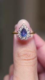 A video of a vintage sapphire and diamond cluster engagement ring being turned in the hands whilst held. 