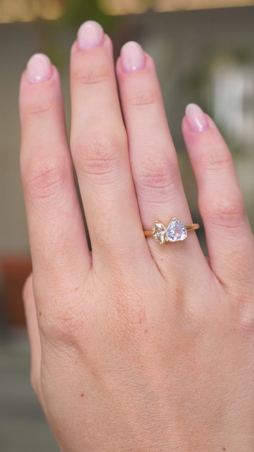 A video of a yellow gold Antique-inspired, colourless sapphire and brown natural diamond toi et moi two stone engagement ring worn on a hand that slowly turns.