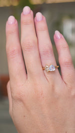 A video of a yellow gold Antique-inspired, colourless sapphire and brown natural diamond toi et moi two stone engagement ring worn on a hand that slowly turns.