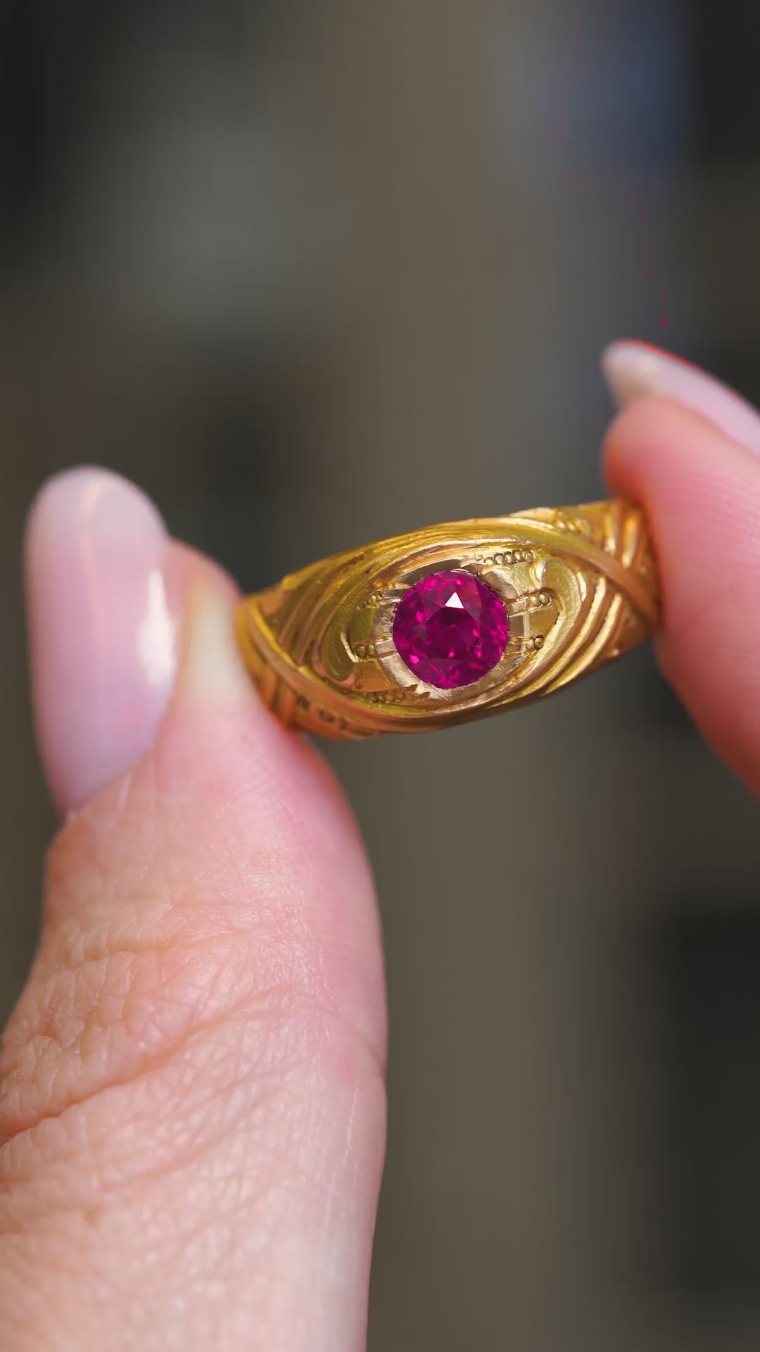 A video of an Antique, Art Nouveau ruby single-stone yellow gold gypsy ring held in the fingers and turned to show angles.