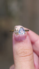 A video of an Antique-inspired, colourless sapphire and marquise brown natural diamond toi et moi two stone engagement ring on a yellow gold band, held between the fingers and turned to showcase different angles.