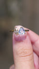 A video of an Antique-inspired, colourless sapphire and marquise brown natural diamond toi et moi two stone engagement ring on a yellow gold band, held between the fingers and turned to showcase different angles.