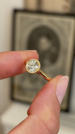 Vintage inspired diamond rub-over solitaire engagement ring featuring a round brilliant-cut diamond in a timeless rub-over setting, held by hand for detailed viewing.