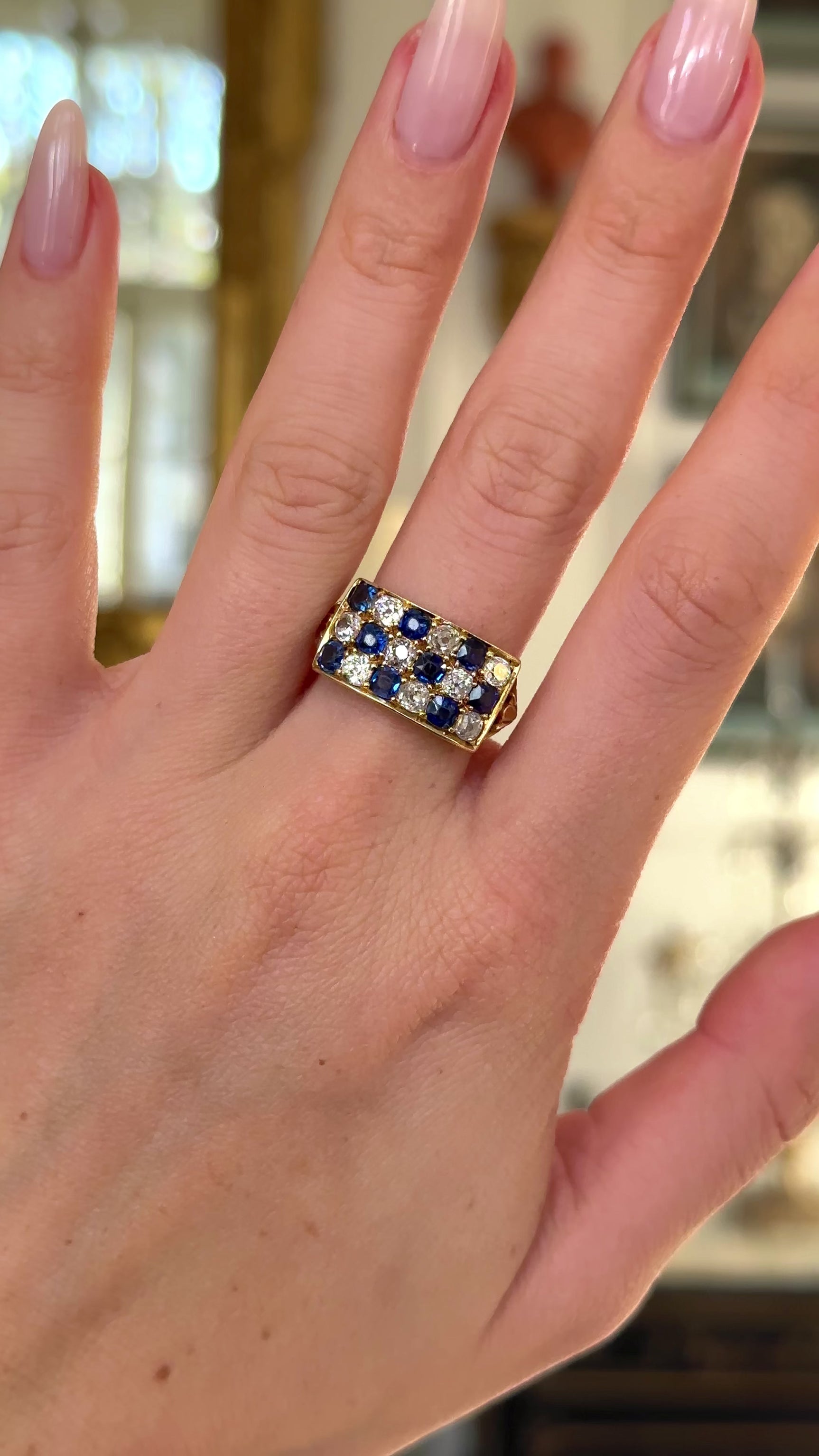 Sapphire and diamond checkerboard ring worn on hand and moved around to give perspective. 
