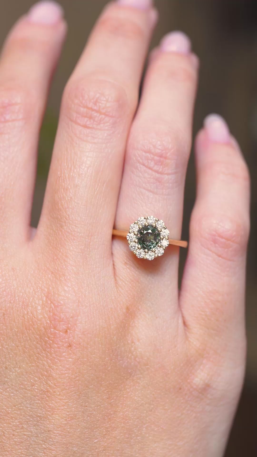 A video of an earthy green sapphire and diamond engagement ring displayed on the hand in an antique-inspired yellow gold setting.