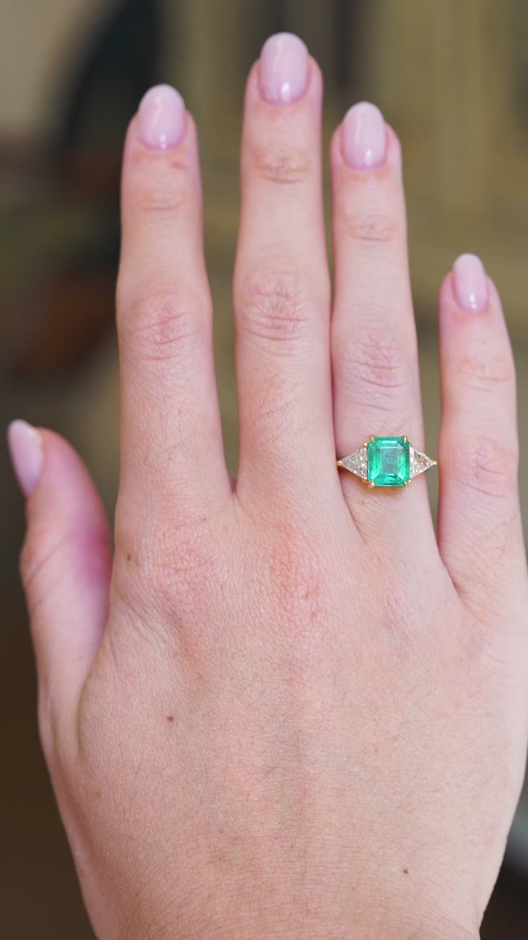 Vintage emerald and diamond three stone ring worn on hand showing emerald colour and diamond sparkle in movement.