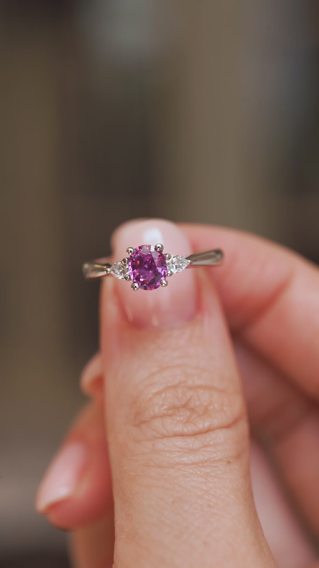 Video close-up of an antique-inspired sapphire ring balanced on a fingertip, displaying its elegant three-stone design.