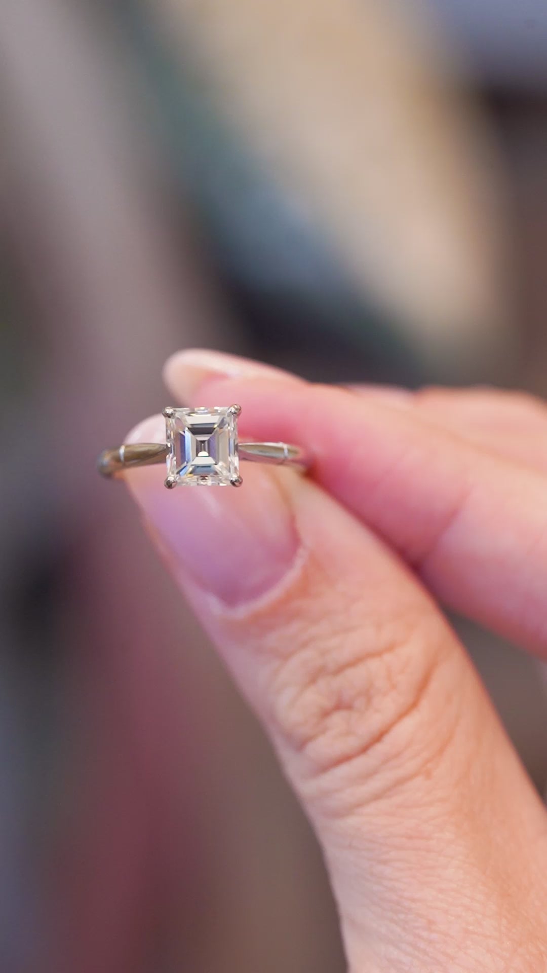 Close detail video of vintage solitaire diamond ring with emerald-cut diamond and elevated setting.