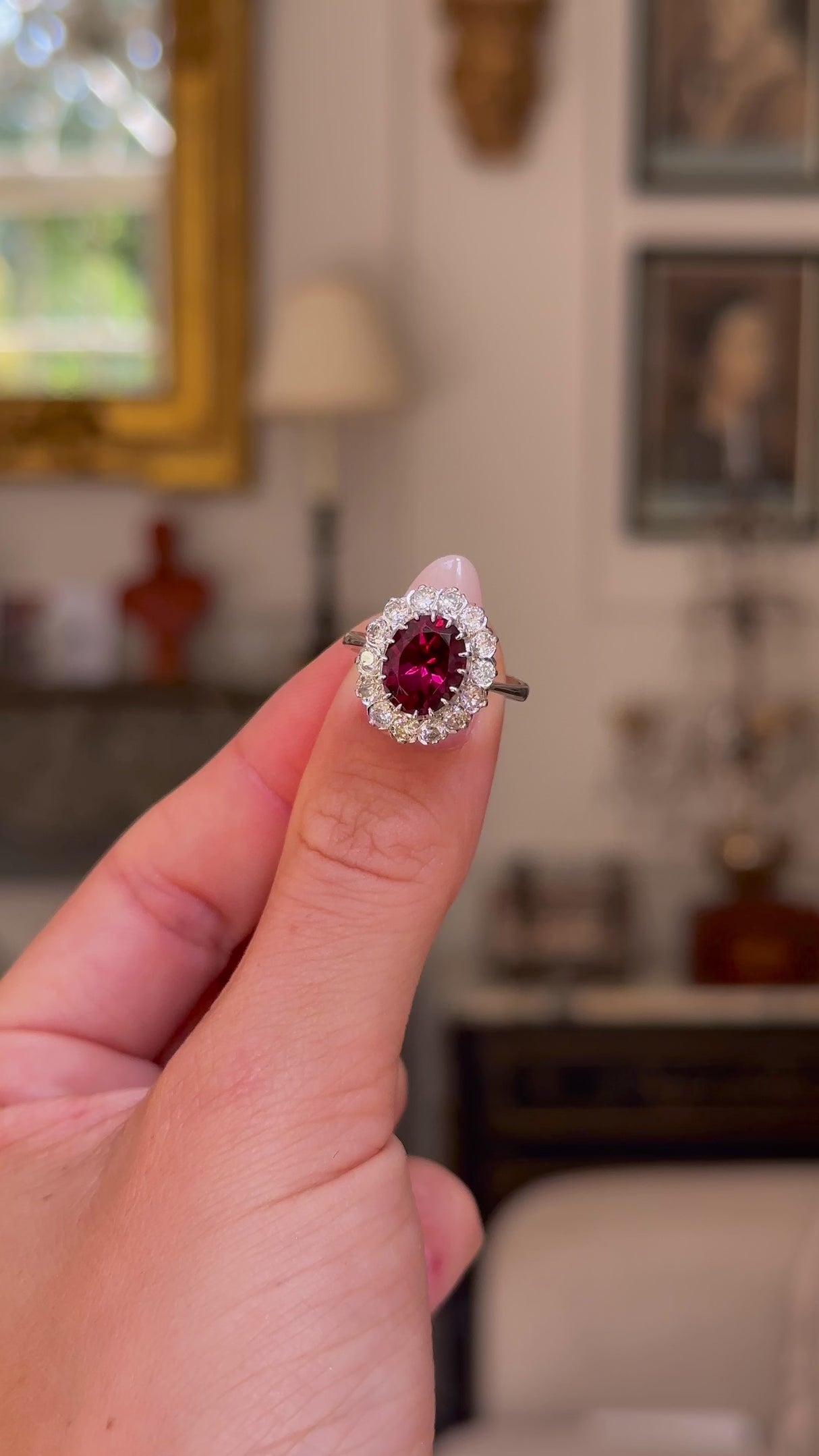 red tourmaline and diamond cluster ring,  held in fingers and rotated to give perspective,front view. 