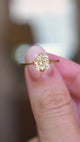A video of a close-up of an antique-inspired yellow-toned cushion-cut diamond solitaire ring in yellow gold held between the fingers.