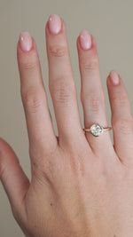 A video of the old mine-cut diamond engagement ring worn on a finger, capturing the stone's broad facets and warm reflections within its gold setting.